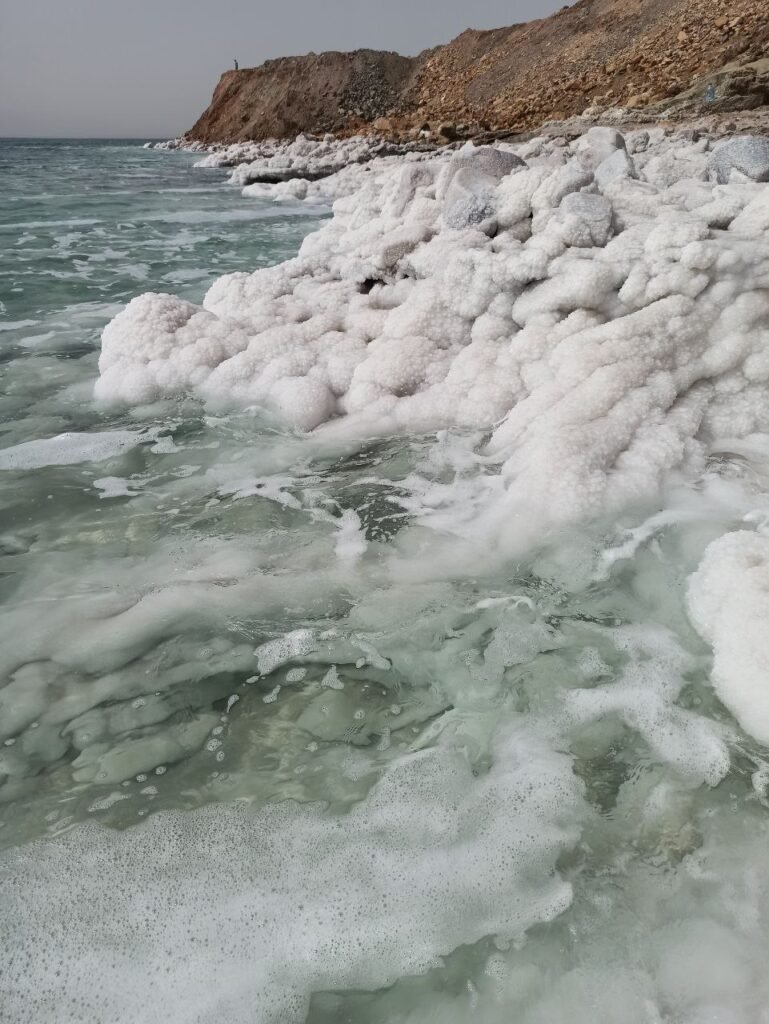 Blick auf die salzverkrustete Küste des Toten Meeres mit türkisfarbenem Wasser – natürliche Quelle für Magnesiumchlorid und Grundlage für die Wirkung von Magnesiumöl bei Muskelverspannungen und Unruhe.